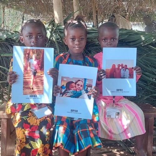 Kinderen laten foto sponsor zien op sponsorkindfeest in Sierra Leone