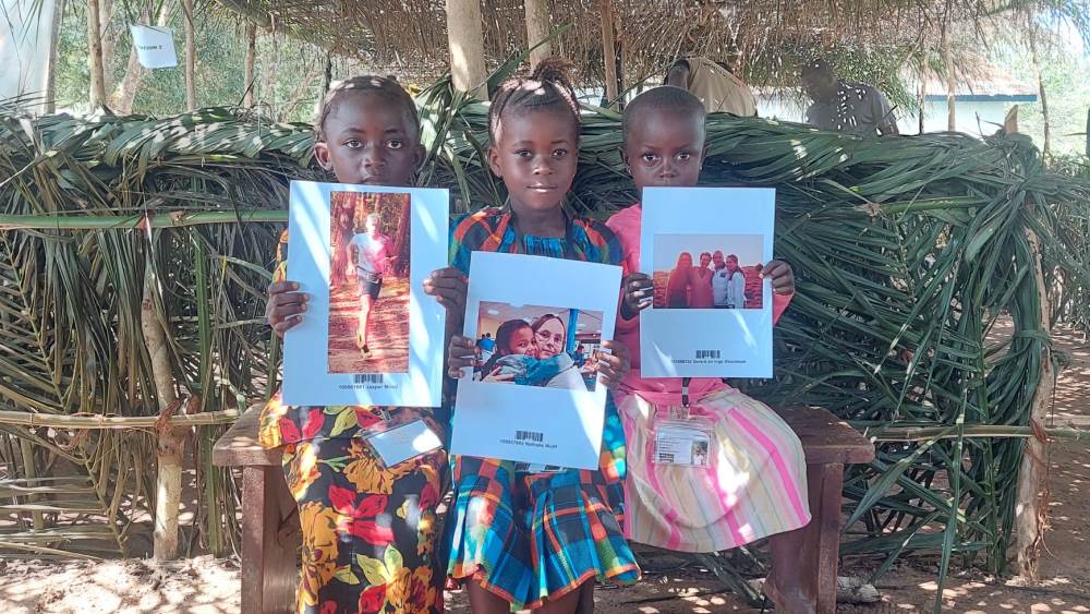 Kinderen laten foto sponsor zien op sponsorkindfeest in Sierra Leone