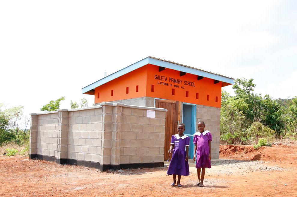 Twee meisjes staan voor nieuw toiletgebouw bij school in Malawi