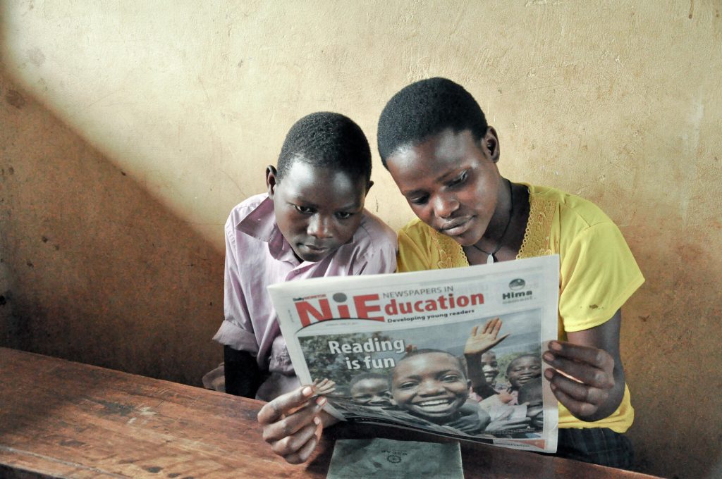 Kinderen lezen de krant tijdens hun les op school in Oeganda
