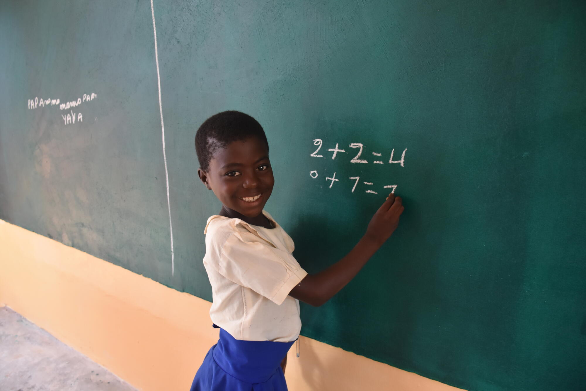 Een meisje schrijft rekensommen op het schoolbord op school in Congo.
