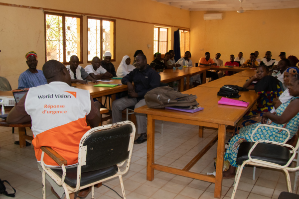 Groep mensen krijgt voorlichting van World Vision medewerker