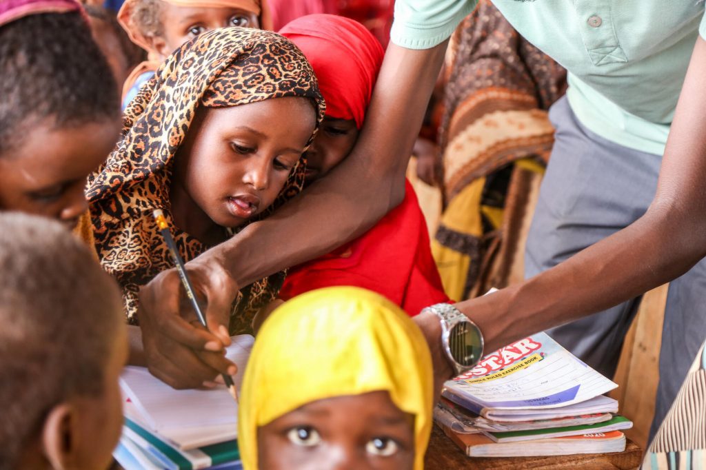 Meisje uit Somalië krijgt uitgelegd hoe ze moet schrijven op school