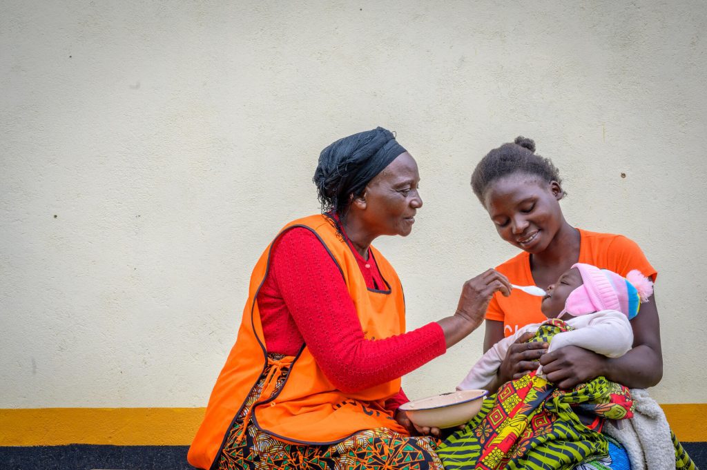 World vision medewerker geeft een kind eten