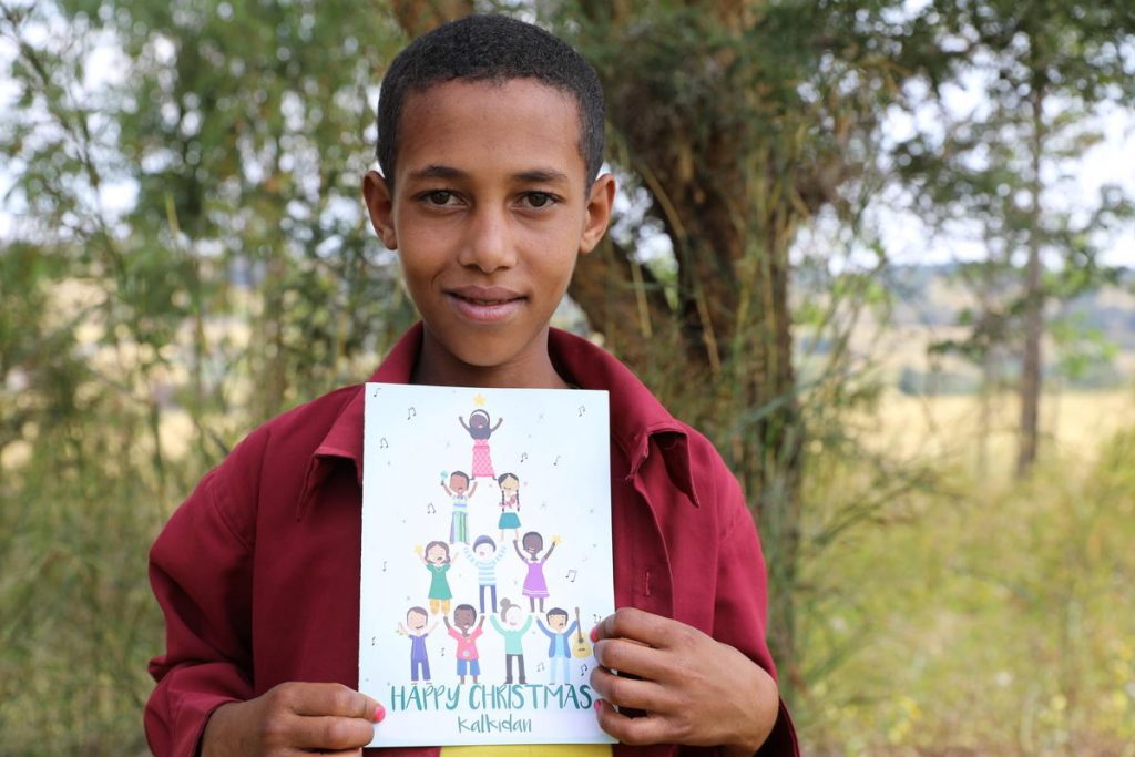 Een jongen houdt een kerstkaart omhoog die hij heeft gehad van zijn sponsor.
