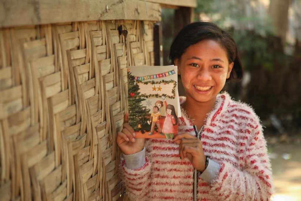 Een meisje uit Myanmar houdt een kerstkaart vast